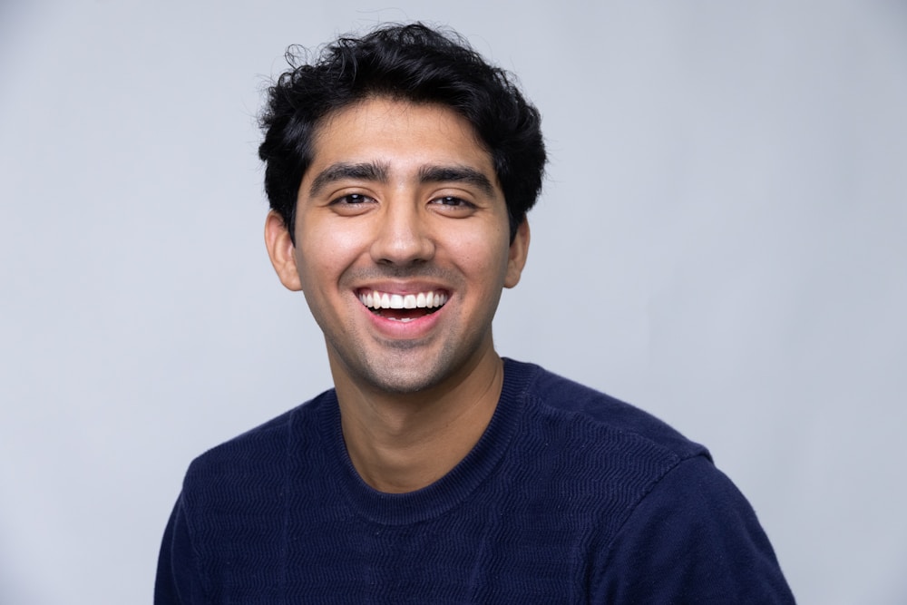 A commercial headshot: warm, open, eyes to camera, plain studio background