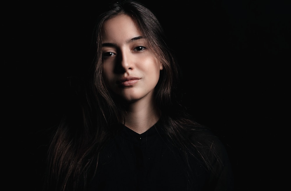 A dramatic headshot: cooler light, neutral expression, more contrast, plain dark background